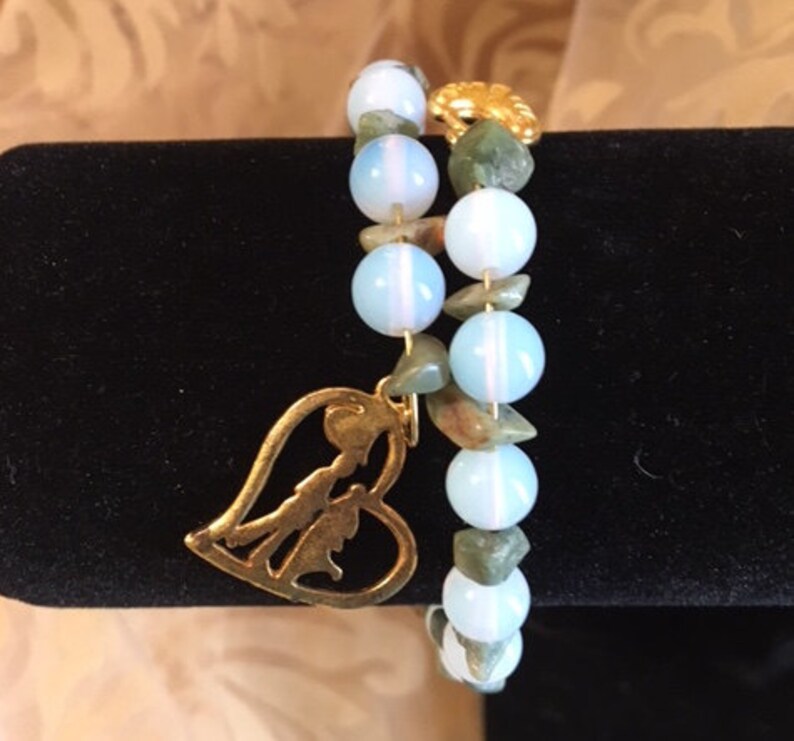 May include: A double-strand bracelet with light blue and green gemstone beads and a gold heart charm.