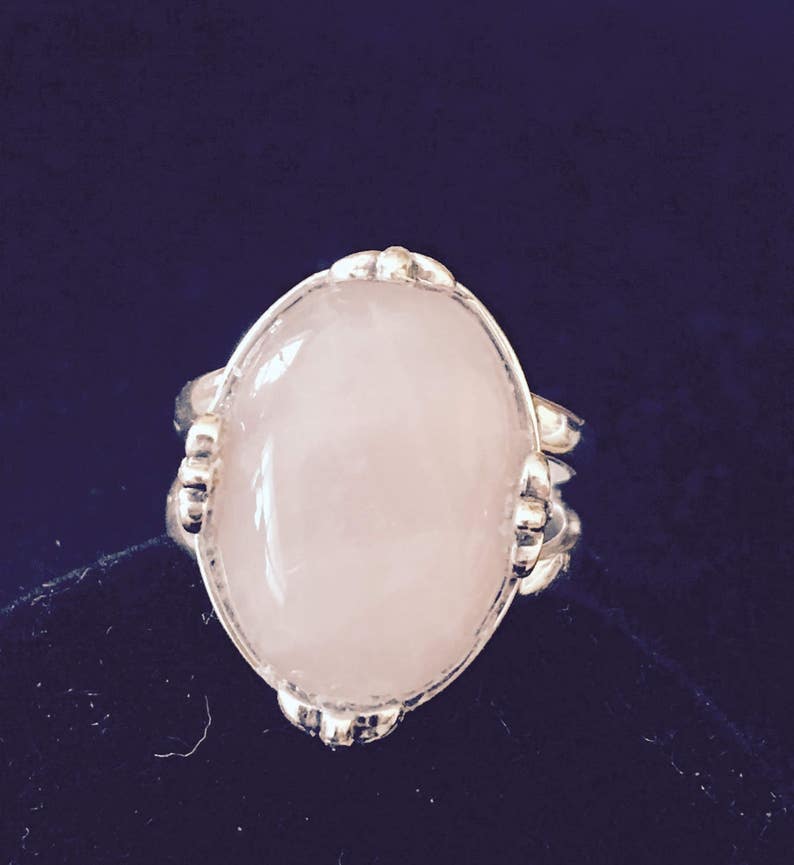 May include: A silver ring with a large oval-shaped rose quartz gemstone.