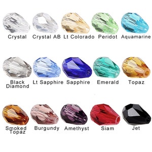 May include: A collection of teardrop-shaped crystal beads in various colors, including clear, blue, green, and amber. Each bead is labeled with its color name, such as "Crystal," "Sapphire," and "Emerald."
