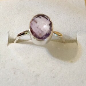 Pu&ograve; includere: Un anello d'argento con una pietra ovale di colore viola chiaro.