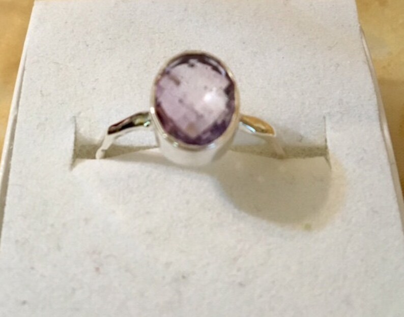 Pu&ograve; includere: Un anello d'argento con una pietra ovale di colore viola chiaro.