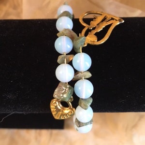 May include: Two bracelets with light blue and green beads and gold heart charms.