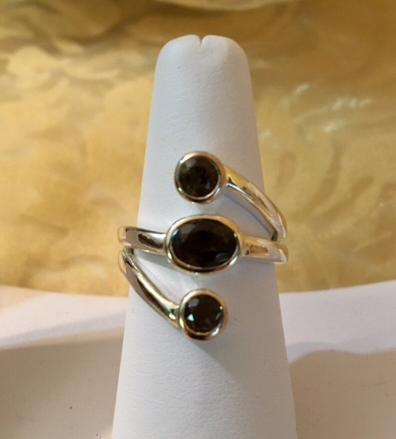 Peut inclure: Une bague en argent avec trois pierres ovales brun fonc&eacute; serties dans une bande torsad&eacute;e.