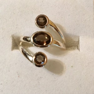 Peut inclure: Une bague en argent avec trois pierres ovales brunes. La bague est con&ccedil;ue avec une bande torsad&eacute;e.