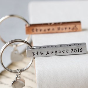 May include: Silver keyring with a heart charm and a silver bar engraved with "Kerry & Owen 8th August 2015".