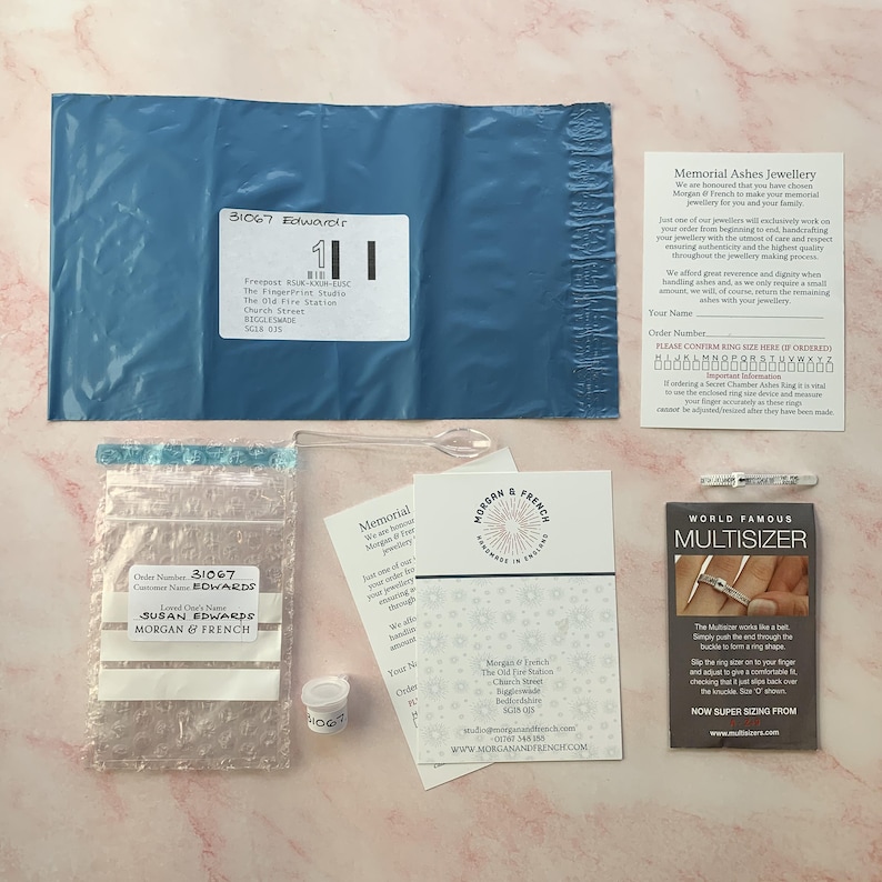 May include: An overhead shot of a package containing memorial jewelry from Morgan & French. The package includes a blue envelope, a ring sizer, a small vial, and informational cards. The order is for Susan Edwards.