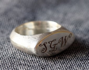 May include: A silver signet ring with an oval top engraved with the initials "S.G.W."