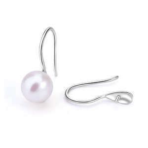 May include: A pair of silver dangle earrings with a single white pearl on each earring.