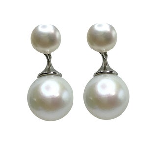 Op de afbeelding: Een paar zilveren oorbellen met twee witte parels aan elke oorbel.