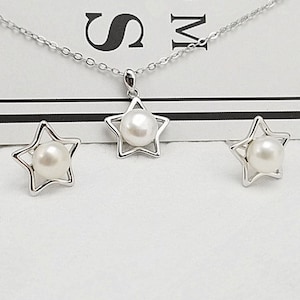 May include: A silver necklace and earrings set featuring a star-shaped pendant and earrings with a pearl in the center of each star.