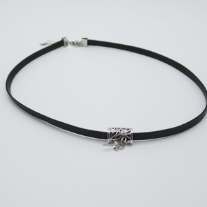 May include: A black choker necklace with a silver pendant featuring a floral design.