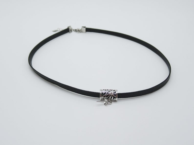 May include: A black choker necklace with a silver pendant featuring a floral design.