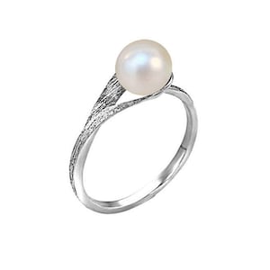 May include: A silver ring with a textured band and a single white pearl.