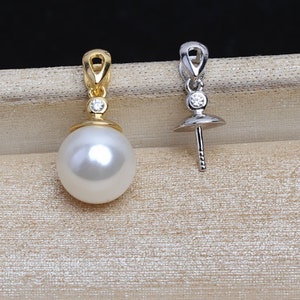 May include: Two pearl necklace clasps, one gold and one silver, with a small clear rhinestone accent. Both clasps have a loop at the top for attaching a necklace.