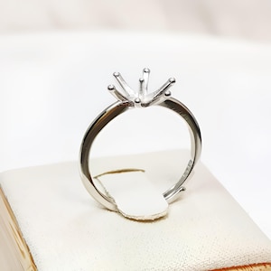 May include: A silver ring setting with a six-prong solitaire setting.