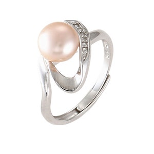 May include: A silver ring with a large, round, light pink pearl set in a twisted band. The band is accented with small, clear stones.