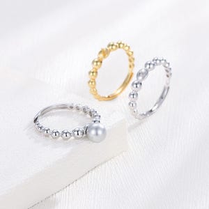 May include: Three adjustable rings with a beaded design. One ring is silver with a pearl accent. One ring is gold and one ring is silver.