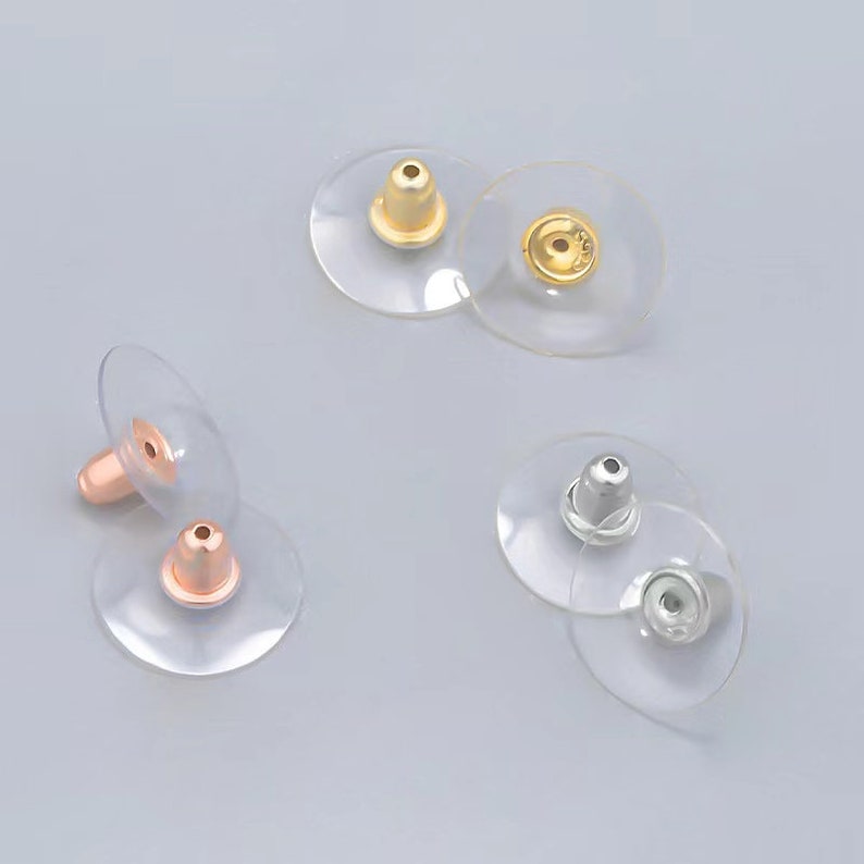 Puede incluir: Tres pares de respaldos para pendientes en oro, oro rosa y plata. Cada par tiene un respaldo de pl&aacute;stico transparente con un poste de metal.