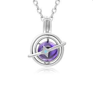 Puede incluir: Un collar de plata con un colgante de piedra preciosa púrpura y azul. El colgante es una esfera con un anillo de plata alrededor, y una estrella de plata más pequeña con una piedra preciosa azul en el centro. El collar está sobre un fondo blanco.