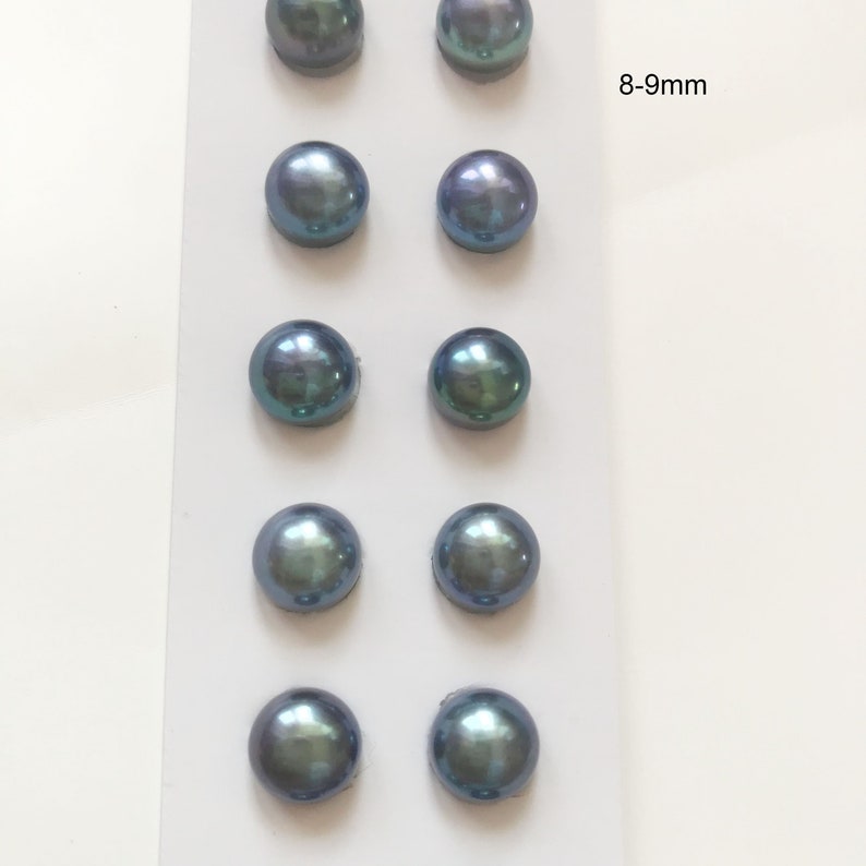May include: Eight round, iridescent blue pearls, each measuring 8-9 mm, are displayed on a white card. The pearls are arranged in four rows of two pearls each.