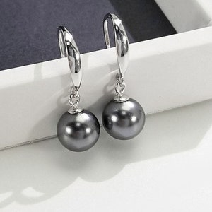 May include: A pair of silver dangle earrings with black pearl drops.