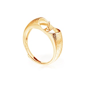 May include: Gold-toned ring with a textured finish and a round opening for a pearl or gemstone.