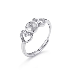 May include: Silver ring with three heart-shaped settings, one with a round pearl bezel. The ring is adjustable.