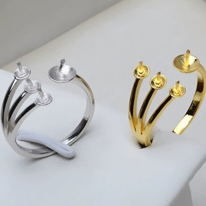 May include: Two adjustable rings with three prongs each, one silver and one gold, for attaching beads or charms.