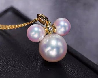 May include: A gold pendant necklace with three white pearls and a small diamond accent. The pearls are arranged in a cluster, with the largest pearl in the center.