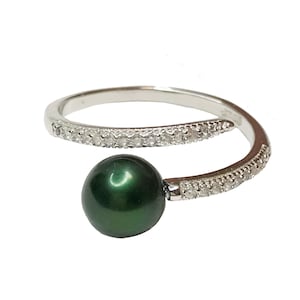 Puede incluir: Un anillo de plata con una perla verde oscura y una banda de pequeños diamantes.