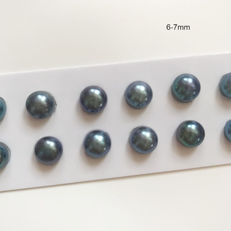 May include: A close-up of ten blue-grey pearls, each measuring 6-7mm, arranged in rows on a white card.