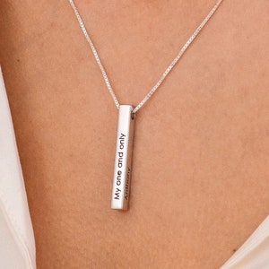 May include: A silver necklace with a vertical bar pendant engraved with the text "My one and only" and "Anthony".