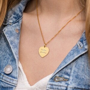 May include: A gold heart-shaped pendant necklace with the names "Caroline" and "Jonathan" engraved on it.
