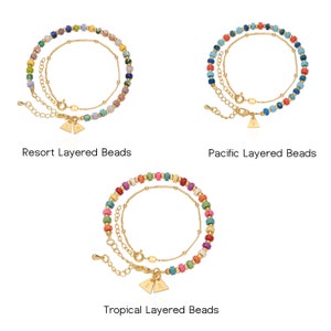 Pu&ograve; includere: Tre set di braccialetti a strati con perline, catene dorate e ciondoli triangolari. I braccialetti sono in diverse combinazioni di colori: blu, verde e rosa; blu, rosso e turchese; e multicolore.