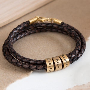 May include: A brown leather bracelet with three gold beads engraved with the names "Andrew", "Alan", and "Charlie".