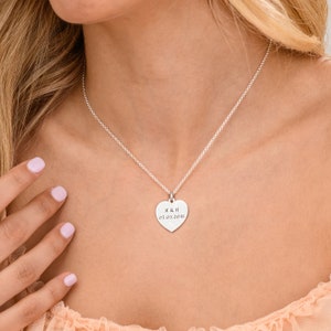 May include: A silver heart-shaped pendant necklace with the inscription "M & H 05.09.2018".