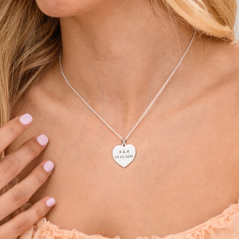 May include: A silver heart-shaped pendant necklace with the inscription "M & H 05.09.2018".