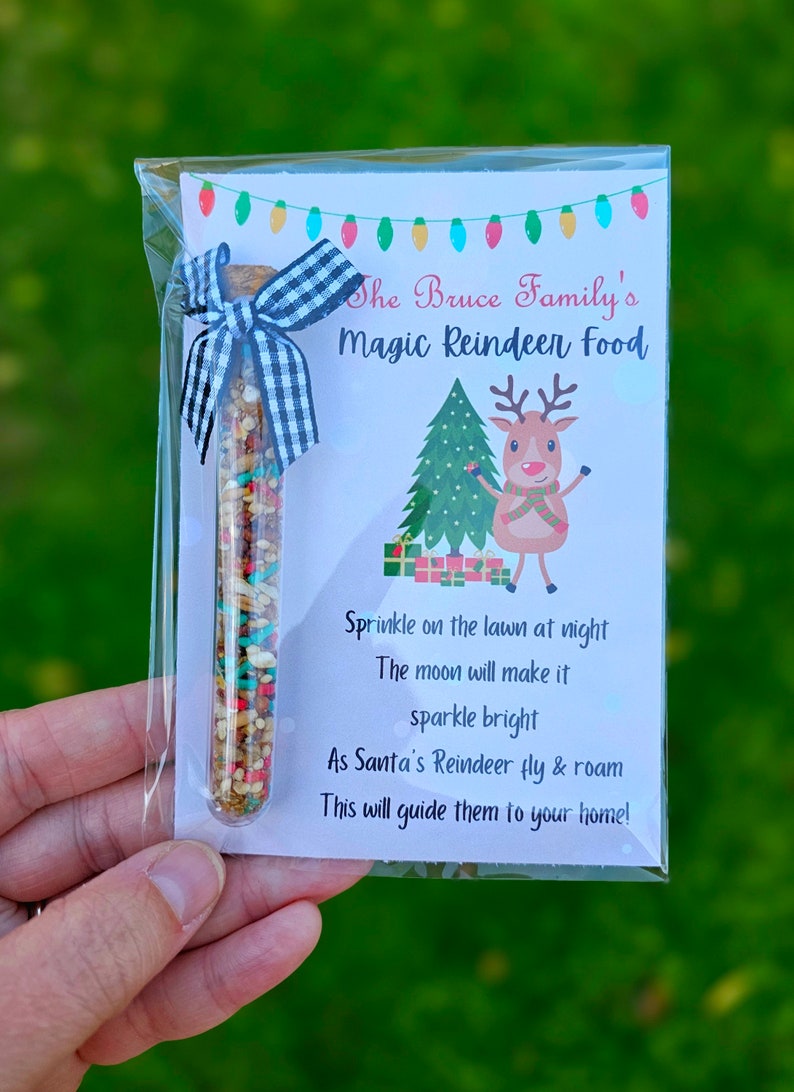 May include: A clear plastic tube filled with colorful sprinkles and a white and black checkered ribbon tied around the top. A white card with the text "The Bruce Family's Magic Reindeer Food" and instructions for using the sprinkles is behind the tube. The card also features a cartoon reindeer.