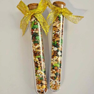 May include: Two clear glass test tubes filled with a variety of small, colorful seeds and grains. The tubes are topped with cork stoppers and tied together with a gold ribbon.