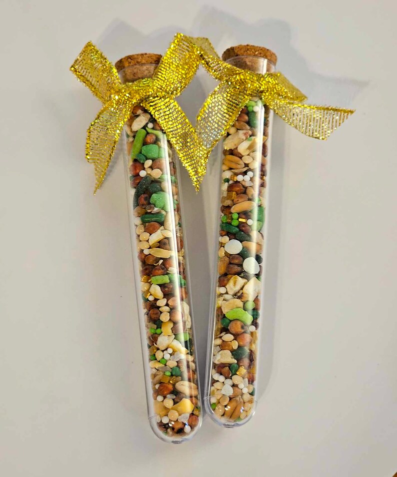 May include: Two clear glass test tubes filled with a variety of small, colorful seeds and grains. The tubes are topped with cork stoppers and tied together with a gold ribbon.