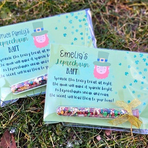 May include: Two clear plastic bags with green and white cards inside. The cards have a leprechaun illustration and the text "The Bruce Family's Leprechaun Bait" and "Emelia's Leprechaun Bait". Each bag contains a small glass vial filled with colorful sprinkles.