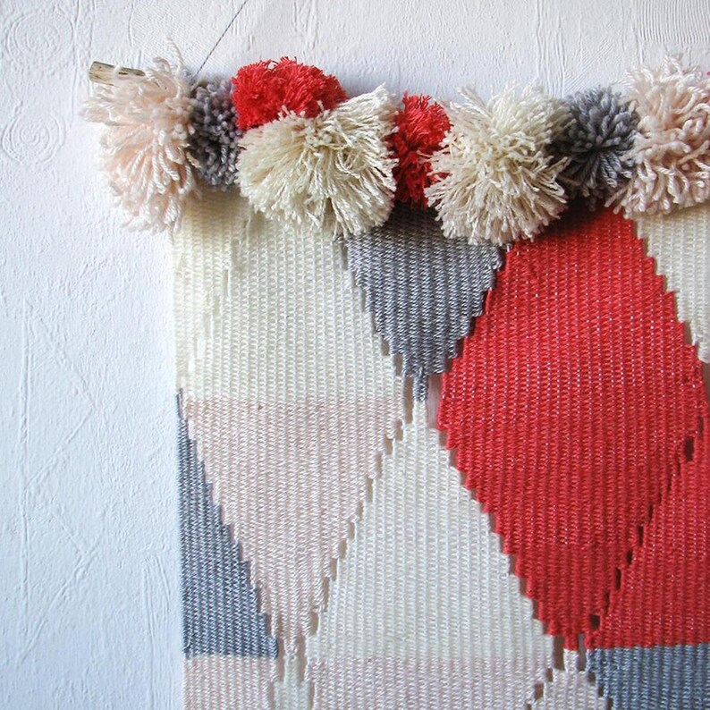 Detail of a woven wall hanging i pink, blue and beige