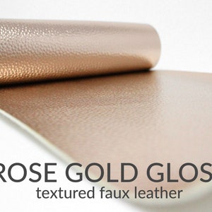 May include: A roll of rose gold gloss textured faux leather. The leather has a subtle pebbled texture.