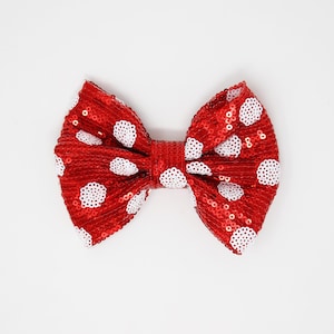 May include: A red bow with white polka dots. The bow is made of a shiny fabric and is perfect for adding a touch of whimsy to any outfit.