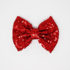 May include: A red sequin bow. The bow is made of small, shiny sequins and is tied in a classic bow shape.