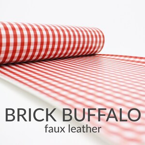 May include: A roll of red and white gingham faux leather fabric. The fabric has a checkered pattern and is labelled "BRICK BUFFALO faux leather".