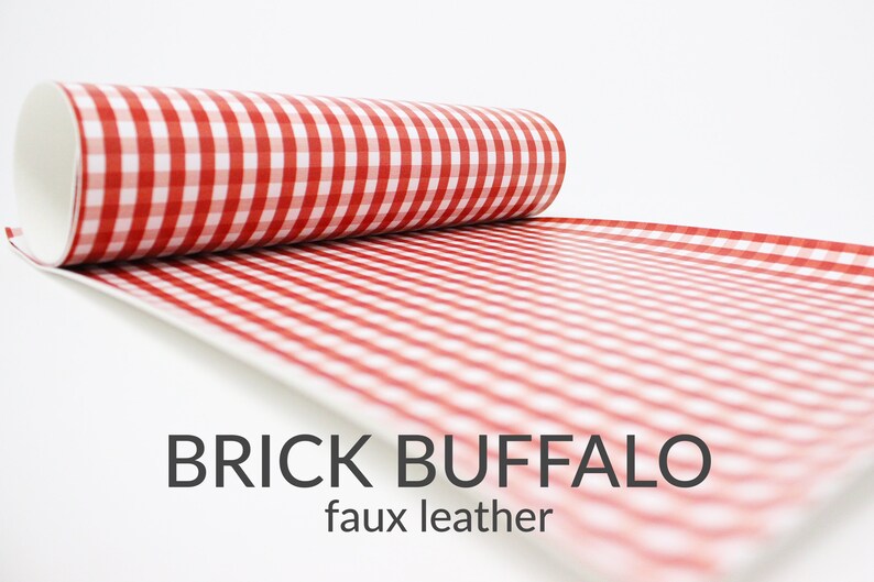 May include: A roll of red and white gingham faux leather fabric. The fabric has a checkered pattern and is labelled "BRICK BUFFALO faux leather".