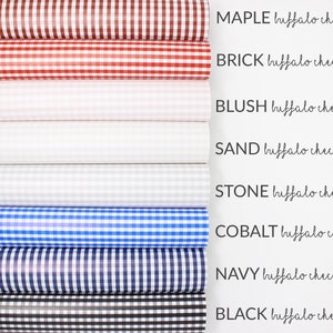 May include: Eight rolls of buffalo check fabric in various colours, including red, white, blue, black, and grey. The fabric is arranged vertically with the colour names and "buffalo check" written next to each roll.