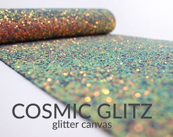 May include: A roll of iridescent glitter canvas fabric with a textured surface. The fabric has a blue, green, and gold color scheme. The text "COSMIC GLITZ glitter canvas" is printed on the fabric.