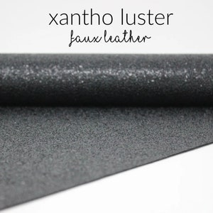 May include: A roll of black faux leather with a textured, pebbled surface. The fabric is called "xantho luster faux leather".